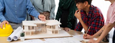 Mimari takım analizi ve ev modeli, plan ve mimari ekipmanlarla toplantı masasında ev inşaatı hakkında beyin fırtınası. Yaratıcı tasarım ve takım çalışması. Filizlenen.