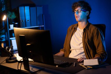 Stresli yaratıcı yönetici yeni sunumla tasarım araması yaparken ev ofisteki dizüstü bilgisayarlı ekranda gece vakti neon lambalı bir odada e-posta göndermeyi bekliyor. Toplayıcı.