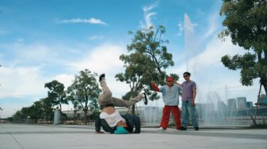 Profesyonel çekici hipster, Fountain ile sokak dansı yapıyor. Yakışıklı bir adamın B-boy ayak egzersizi sahnesi. Mavi arka plan. Modern yaşam tarzı. Açık hava sporu 2024. Yumuşak bir şekilde..