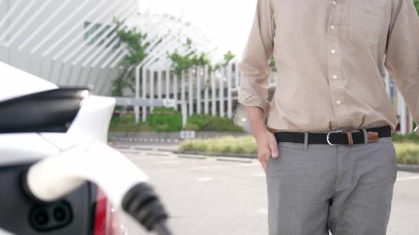 慢动作男子把电动汽车充电器从城市购物中心停车场的充电站充电 作为电动汽车快速在可持续城市使用的可充电能源 — 图库视频影像