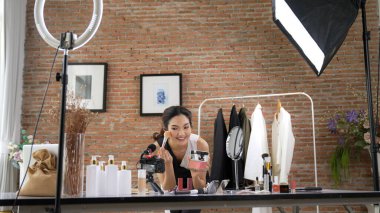 Kadın nüfuzlu kişi canlı yayın yapan video görüntülerini sosyal medya ya da blog üzerinden gözden geçiriyor. Kozmetik stüdyosu ışıklandırmalı mutlu genç kız çevrimiçi pazarlama oturumu yayını için..