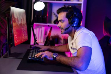 Akıllı oyun flaması dijital neon ışıklı siber odada kulaklık takarak bilgisayar ekranında çoklu ya da tek oyuncuyla çevrimiçi atış oyunu oynayan bir savaş takımı ile oynamaktan zevk alır. Tahmin et..