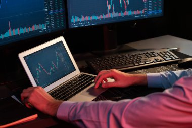 Dizüstü bilgisayarda araştırma yapan genç yatırımcı hisse senedi tüccarı, güncel pazar grafiğinin dinamik döviz kuru ekranlarıyla gerçek zamanlı olarak neon ışığı modern ofisinde finansal verileri analiz ediyor. Toplayıcı.