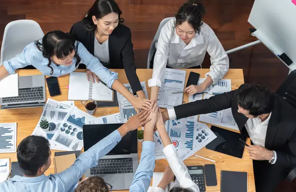 Multiracial business people make synergy hand stack together in meeting room as cooperation or team building for corporate employee in workplace. Top view. Meticulous