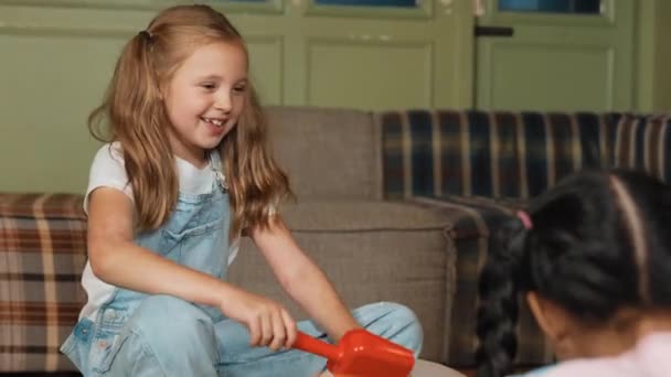 Szczęśliwa Dziewczyna Bawi Się Zabawką Różnorodnym Dzieckiem Siedząc Pokoju Zabaw — Wideo stockowe