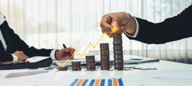 Dijital grafik göstergeli bozuk para yığını iş yatırımını ve ekonomik büyümeyi sembolize ediyor. Finansal hedefe ulaşmak ve kâr sağlamak için finansal planlama yapan bir iş adamı. Kurnaz.