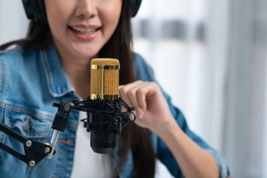 Sosyal medyada kulaklıklar takarak, modern stüdyoda dinleyicileri selamlayarak canlı yayın yapan Asyalı etkili sunucunun görüntüsünü kestim. Taktik.