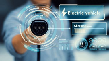 Kameranın önündeki EV şarj aletine odaklan. Bulanık arka planda akıllı batarya durum hologramını göster. Karbondioksit salınımını azaltmak için temiz enerji kullanan elektrikli araba şarjı.