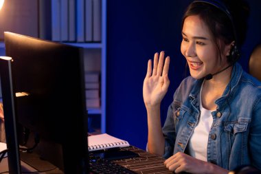 Sunucu kanalı Asyalı etkileyicisi canlı yayında konuşuyor. Sosyal medyada kulaklık takıyor, bilgisayar kaydı yapıyor, dinleyicileri selamlıyor ve Neon Modern Stüdyoları 'nda online olarak koçluk yapıyor. Taktik.