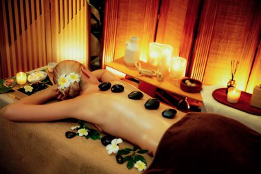 Lüks tatil köyündeki kaplıcalarda sıcak taş masajı, sıcak mum ışığı, spa bazalt taşı masajının keyfini çıkaran mutlu kadın müşteriler, rahatlatıcı bir sıcaklıkla vücudun üzerinde süzülüyorlar. Sessiz.