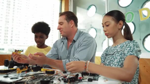 Qualifizierte Lehrer Erklären Afrikanischen Jungen Elektrogeräte Während Gymnasiastinnen Modelle Reparieren — Stockvideo