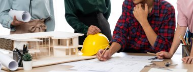 Becerikli mimar takımının tasviri, Mimarlık projesini ev modelleri ve mimari ekipmanlarla toplantı masasında tartışıyor. Yaratıcı tasarım konsepti. - Yakın çekim. Filizlenen.