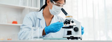 Laboratuvar araştırmacısı mikroskop kullanarak yeni ilaç ya da tedavi geliştirir. Laboratuvar mikrobiyoloji ekipmanları ile bilimsel uzmanlık ile sağlık hizmetlerinin teknolojik gelişimi. Panorama Katı