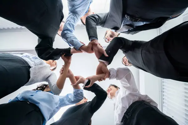 Multicultural business people holding hand together in circle. Unity teamwork in office business workplace. Diverse ethnic office worker engaged in team building. Below view. Habiliment