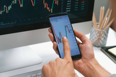 Akıllı borsa yatırımcıları ekranda akıllı telefon ile piyasa borsasını işaret ederek dizüstü bilgisayarın yanı sıra en yüksek dinamik yatırım oranını göstererek, modern işyerindeki veri planlamasına odaklanıyorlar. Bireysel.