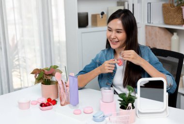 Genç, güzel Asyalı makyaj fırçası yanak testi koleksiyonunu pastel renkle inceliyor. Sosyal medyada akıllı telefonu tanıtmak için pembe ile ışıltılı bir ruh hali sergiliyor. Taktik.