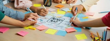 Yaratıcı iş adamları, zihin haritalama kullanarak pazarlama stratejisi ve iş planı hakkında beyin fırtınası yapıyorlar. Girişim ekibi kağıda yazmak için birlikte çalışır. Eline odaklan. - Yakın çekim. Değiştirilmiş.