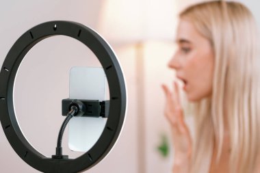 Sosyal medya için güzellik ve kozmetik video içeriği hazırlayan bulanık genç bir kadın. Güzellik etkileyicisi seyircilere ya da takipçilere güzellik hizmetinin nasıl uygulanacağını gösterirken odaklanmış kamera. Blithe