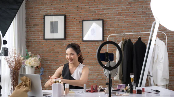 Woman influencer shoot live streaming vlog video review skincare for social media or blog. Happy young girl with vivancy cosmetics studio lighting for marketing recording session broadcasting online.