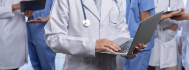 Hastanede dizüstü bilgisayar ve tabletle birlikte çalışan doktor hemşire ve sağlık uzmanlarına sahip tıbbi personel ekibi. Panoramik pankartta tıbbi işyeri ve sağlık hizmetleri topluluğu. Neoterik