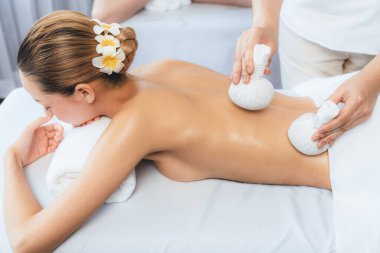 Sıcak bitkisel top spa masaj vücut tedavisi, masör nazikçe bitki torbasını çift müşteri vücuduna bastırıyor. Aromaterapi dinlenme sükuneti ve sükuneti kaplıca salonundaki atmosferi aydınlatıyor. Sessiz.