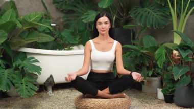 Sabah yoga ve meditasyon yapan genç bir kadın bitki yaprağıyla doğal bahçede yalnızlığın tadını çıkarıyor ve meditasyon yapıyor. Farkındalık aktivitesi ve sağlıklı zihin yaşam tarzı. Blithe