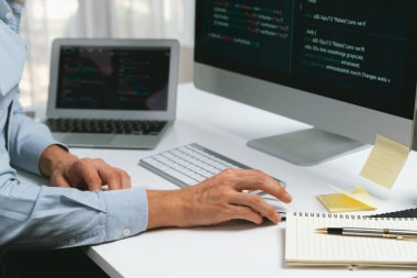 Bilgisayarda bilgisayar ve bilgisayar üzerinde çalışan ve uygulama projesinde kodlama programı olan bilgisayar geliştiricisinin kırpılmış görüntüsü. Teknik mühendis önemli not listeleri yazıyor. Bireysel.