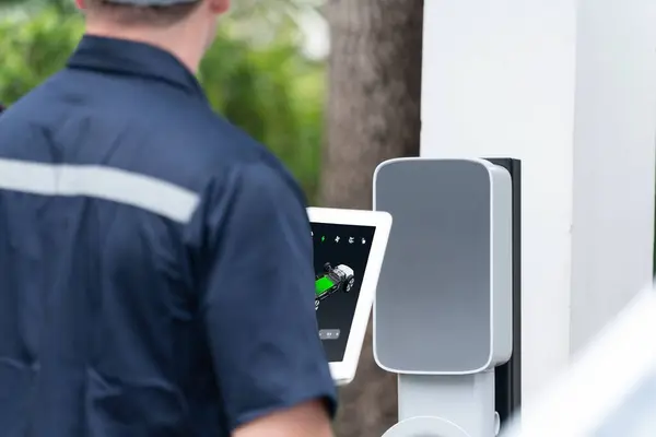 Qualified technician install home EV charging station, providing maintenance service for electric vehicles battery charging platform at home. EV car technology for residential utilization. Synchronos