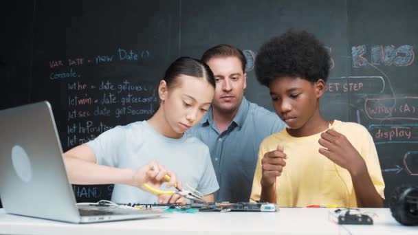 Vit Lärare Talar Elektriska Verktyg Medan Studenten Fastställande Robotmodell Bordet — Stockvideo