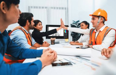 Çeşitli inşaat mühendisi ve müvekkil grupları, mimari proje üzerinde başarılı bir anlaşma yaptıktan, inşaat planını gözden geçirdikten ve toplantı masasında plan oluşturduktan sonra kutlama ve beşlik çakışma yaptılar.