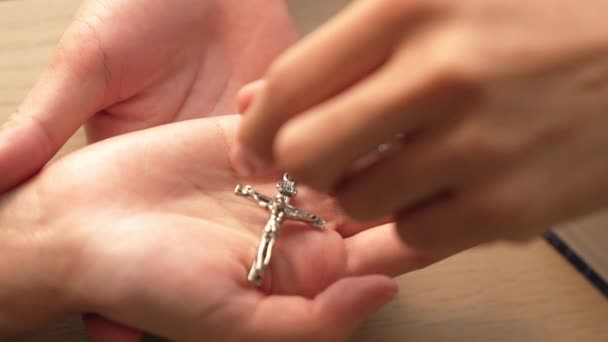 カトリック信仰の変換の行為として もう一方に神聖な十字架を渡すゆっくりとした動き キリスト教徒の信奉者は 愛と犠牲の象徴として十字架と聖書を与えます バージョニング — ストック動画