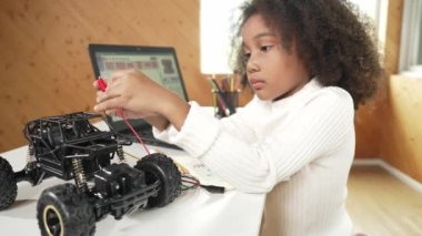 Akıllı Afrikalı kız dizüstü bilgisayar kullanırken ya da komut kodu yazarken kablo kullanırken robotik araba yapıyor. BTMM teknolojisi online sınıfında çalışan yetenekli bir bayan öğrenci. Etkinlik.