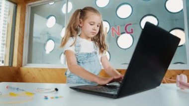 Beyaz kız başarılı bir projeyi kutlamak için kollarını kavuştururken dizüstü bilgisayar programlama yazılımı kullanıyor. Güzel çocuk kodlama sistemi Stem sınıfında gururla ekrana bakarken. Etkinlik.