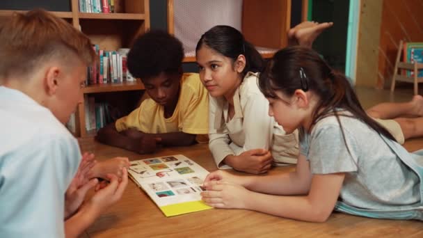 白人聪明的女孩听着年轻的高中生在现代图书馆谈论书本 一组不同种族的学生躺在地板上围成一圈 一边看图画书 — 图库视频影像