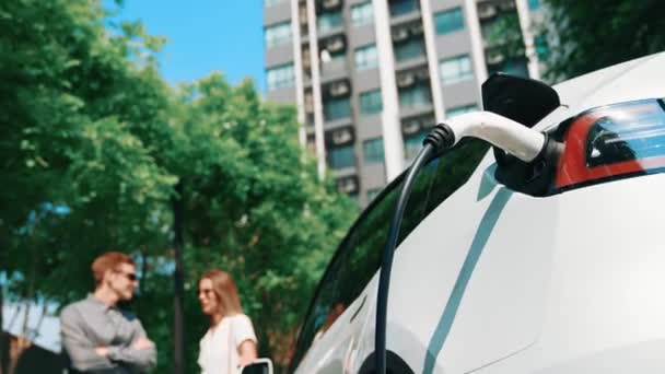 作为城市可持续发展的生活方式 一对年轻夫妇夏季乘坐电动车在绿色可持续城市室外花园充电 以获得电动车内部的清洁充电能量 — 图库视频影像