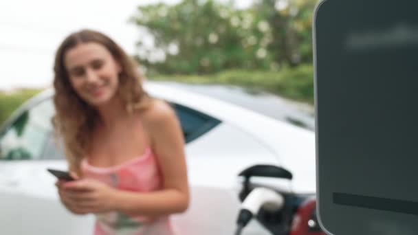 Ev充電ステーションから電気自動車を充電する現代の環境に優しい女性 エネルギー使用量を追跡するための革新的なEv技術の活用は 家庭でのバッテリー充電を最適化します ファスティオディオス — ストック動画