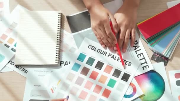 在两位设计师为平面设计工作选择色彩的工作空间表上 或者在设计师创造性的色彩咨询中寻找色彩应用的客户 顶部视图的手工特写 — 图库视频影像