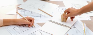 Profesyonel mimar masanın üzerine üzerinde mimari belge ve ahşap bloklar olan bir plan çizer. Tasarım ve Planlama konsepti. Eline odaklan. - Yakın çekim. Tanımlama.