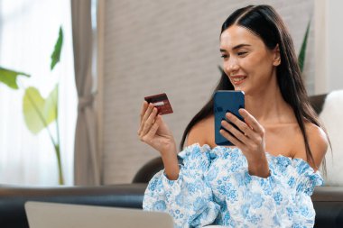 Genç bir kadın kredi kartıyla ödemek için dijital cüzdan ve internet üzerinden ödeme uygulaması kullanıyor. Mobil internet üzerinden alışveriş ve modern alımlar. Blithe