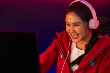 Portre sunucusu güzel Asyalı kız flamasının çevrimiçi oyun oynaması kulaklık takması pastel renkli konuşmalar izleyici medyası ile çevrimiçi. Esport yetenekli takım oyuncuları neon mavi odada. Taktik.