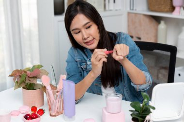 Genç, güzel Asyalı kozmetik makyaj ruju matte pastel rengini modern odadaki sosyal medyada kol testi tanıtımında en çok satanlar listesinde gösteriyor. Taktik.