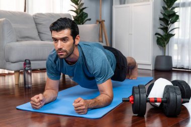 Atletik ve sporcu adam, evde vücut egzersizi yaparken spor ve fiziğe uygun spor yaşam tarzını geliştiriyor. Gaiety evde egzersiz eğitimi.