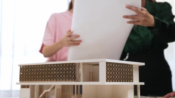 缓慢运动的家庭设计者使用建筑设备评审和测量建筑房屋模型设计样本 与客户或客户一起监督办公室的项目 萌芽状态 — 图库视频影像