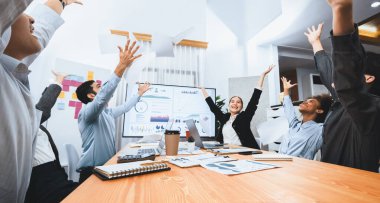 Bir grup ofis çalışanı toplantı odasında kutlama yapıyor, evrak işlerini havaya atıyorlar. İş adamlarından gelen heyecan ve özgürlük ifadesi, finansal analiz kağıtlarını kutlama jesti olarak fırlatıyor. Uyum