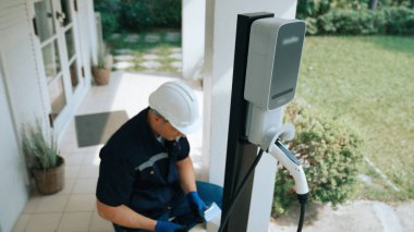 Nitelikli teknisyenler ev EV şarj istasyonu kurarak elektrikli araçların şarj platformu için bakım hizmeti sağlıyorlar. Konut kullanımı için EV araba teknolojisi. Eşzamanlama