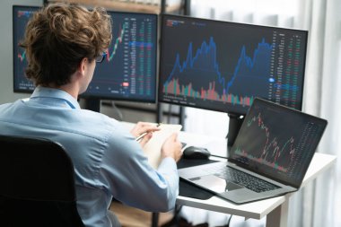 Piyasa stoku grafiği üzerinde çalışan genç profesyonel tüccar ev ofisindeki gerçek zamanlı ekranlara yatırım yaparak önemli döviz kuru kavramları yazarak analiz ediyor. Toplayıcı.