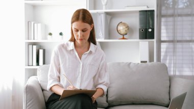 Psikiyatri ofisinde ya da terapi odasında kol koltuğunda oturan profesyonel bir kadın psikolog. Arkadaş canlısı ve ilkel ruh sağlığı danışmanı ve terapisti.