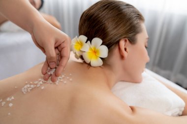 Lüks spa salonlarında sıcak mum ışığında cilt bakımı gören mutlu çift müşterisi. Sağlık kaplıcasında güzellik tedavisiyle tuz temizliği. Sessiz.