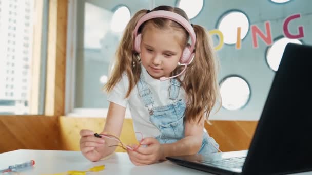 Dziewczyna Nosząca Słuchawki Podczas Nauki Sprzętu Patrząca Kamerę Białe Dziecko — Wideo stockowe