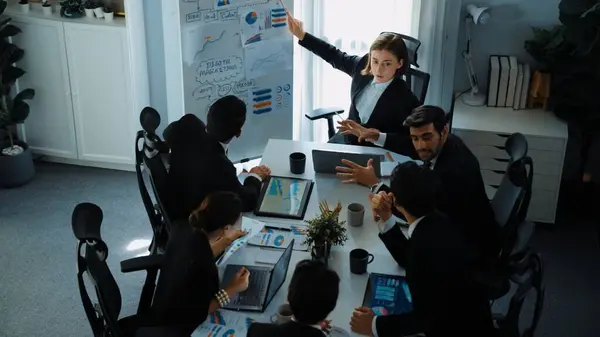 Top view of smart manager project pointing at whiteboard with mind map and financial graph and explain marketing idea while diverse investors listening and analyze stock investment chart. Directorate.